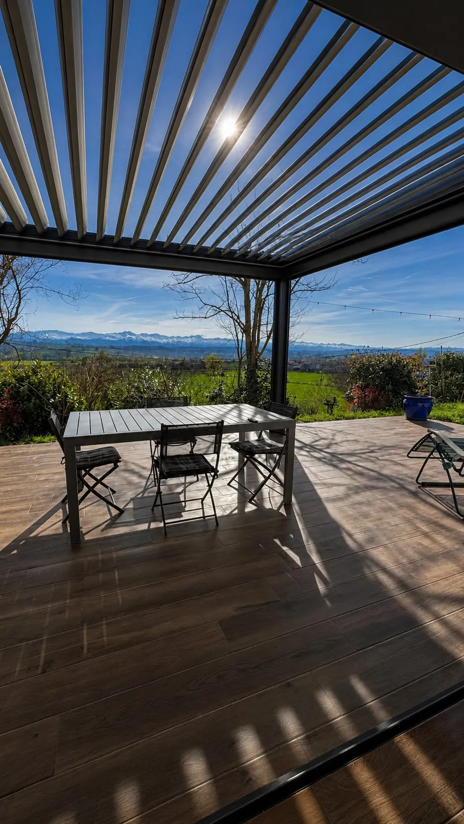 Terrasse sous pergola bioclimatique de la maison de Venerque, avec vue sur la chaîne des Pyrénées.